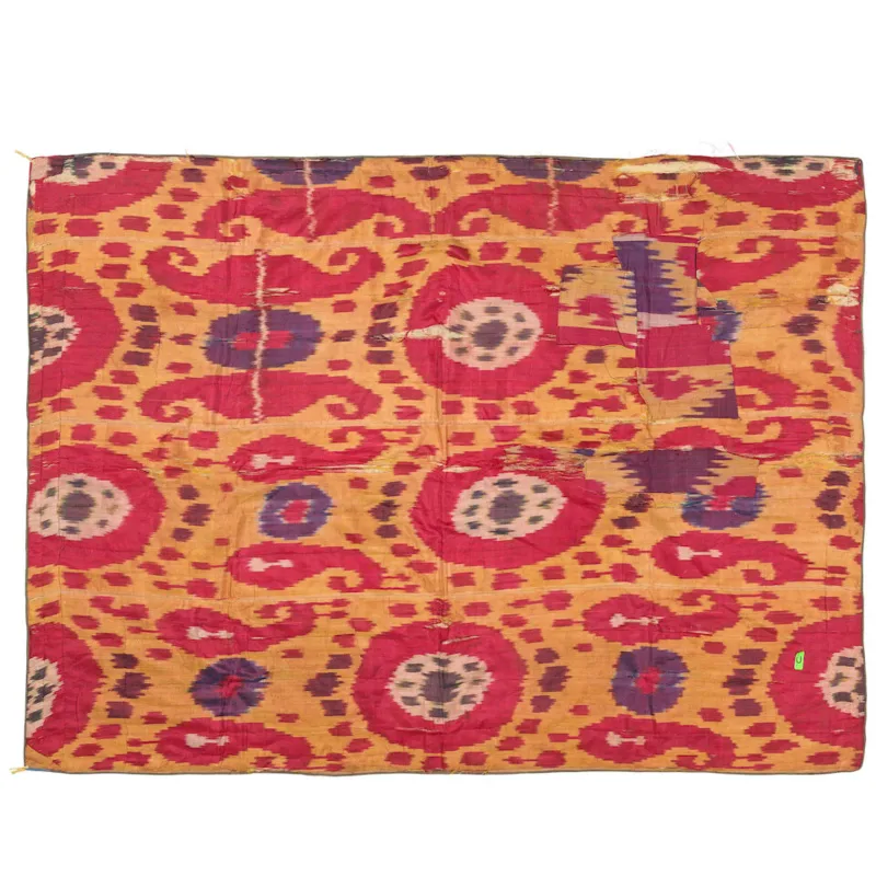 A hanging of silk ikat Uzbekistan, 19th century Composed of joined panels of saffron yellow silk, woven with large red medallions and rams' horn motifs